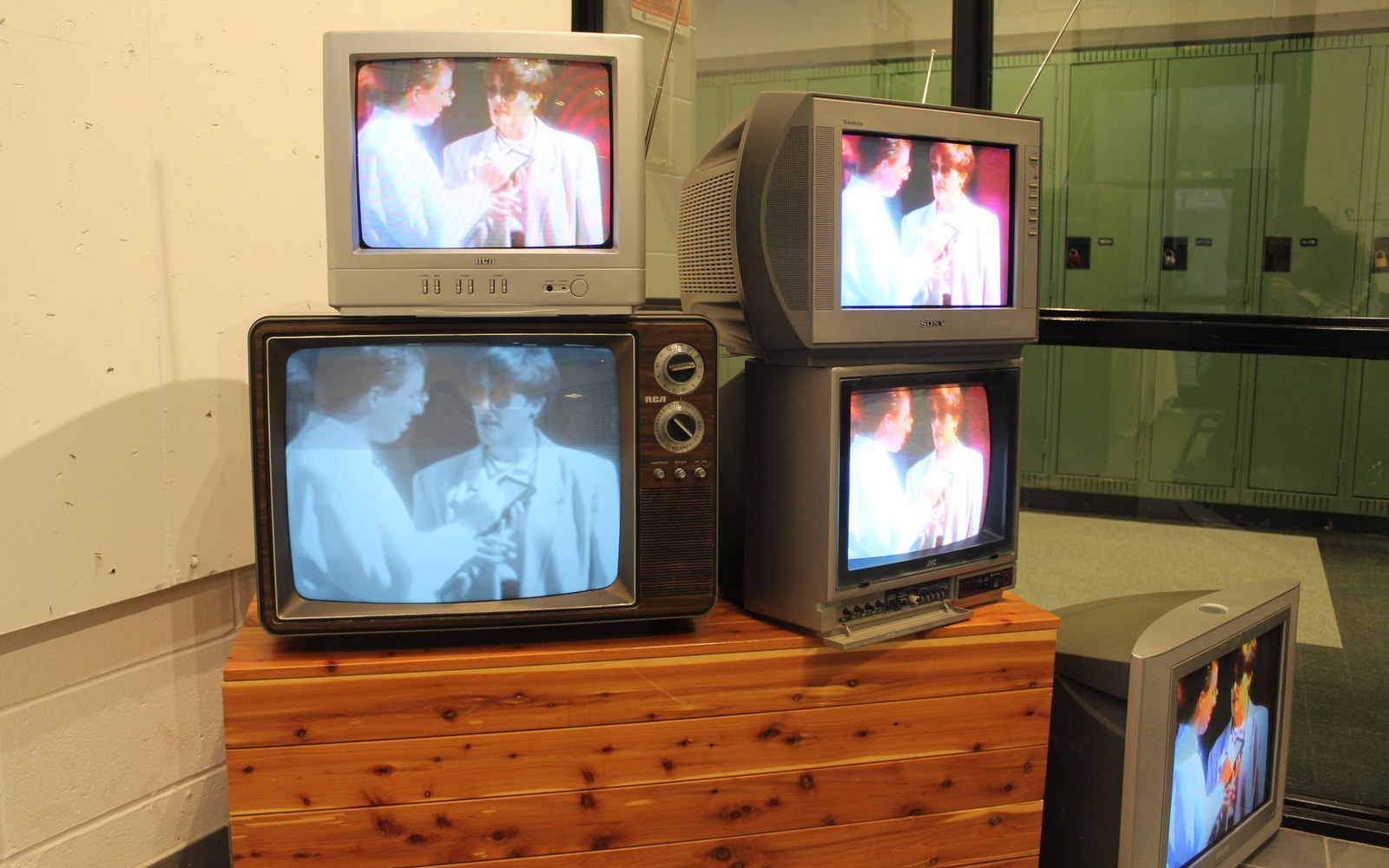 Stacked vintage televisions all displaying the same identical footage of two people talking