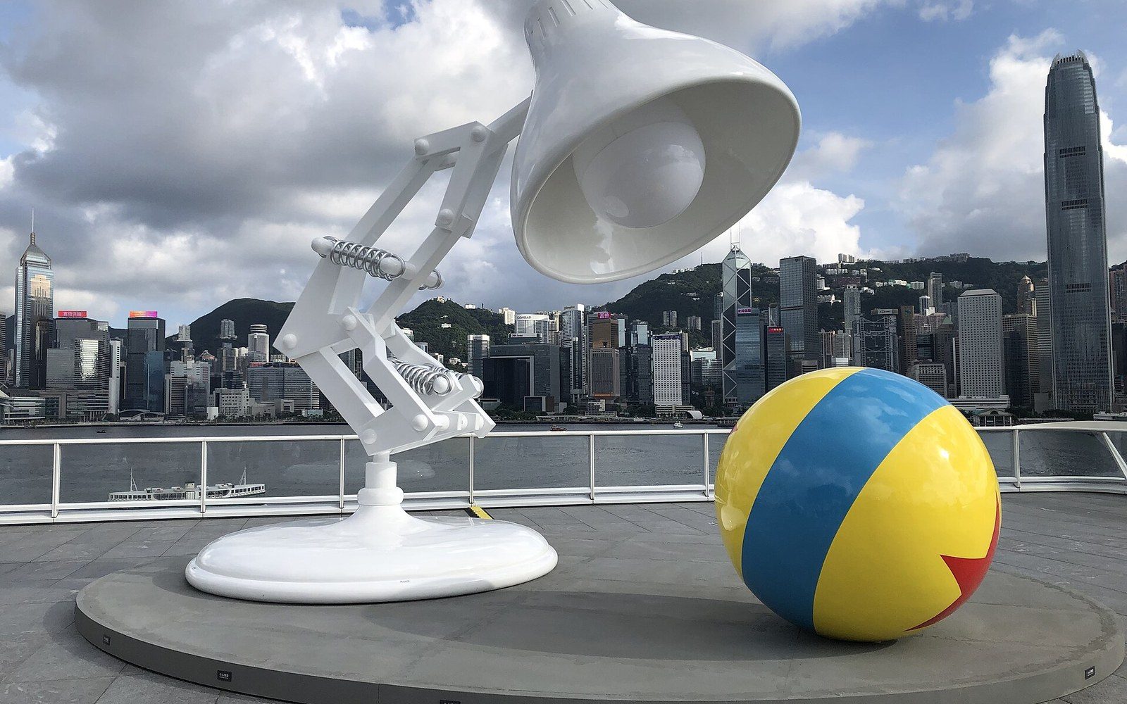 Giant Luxo Jr. lamp statue and striped ball overlook the Hong Kong skyline