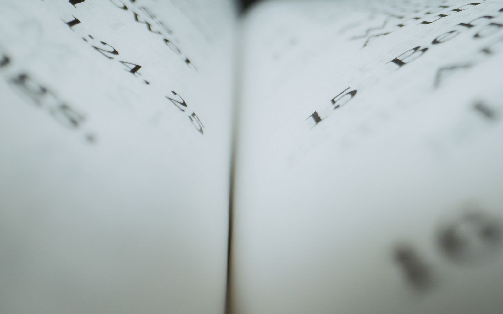 Close-up of an open book's pages showing numbered verse references in blurred focus