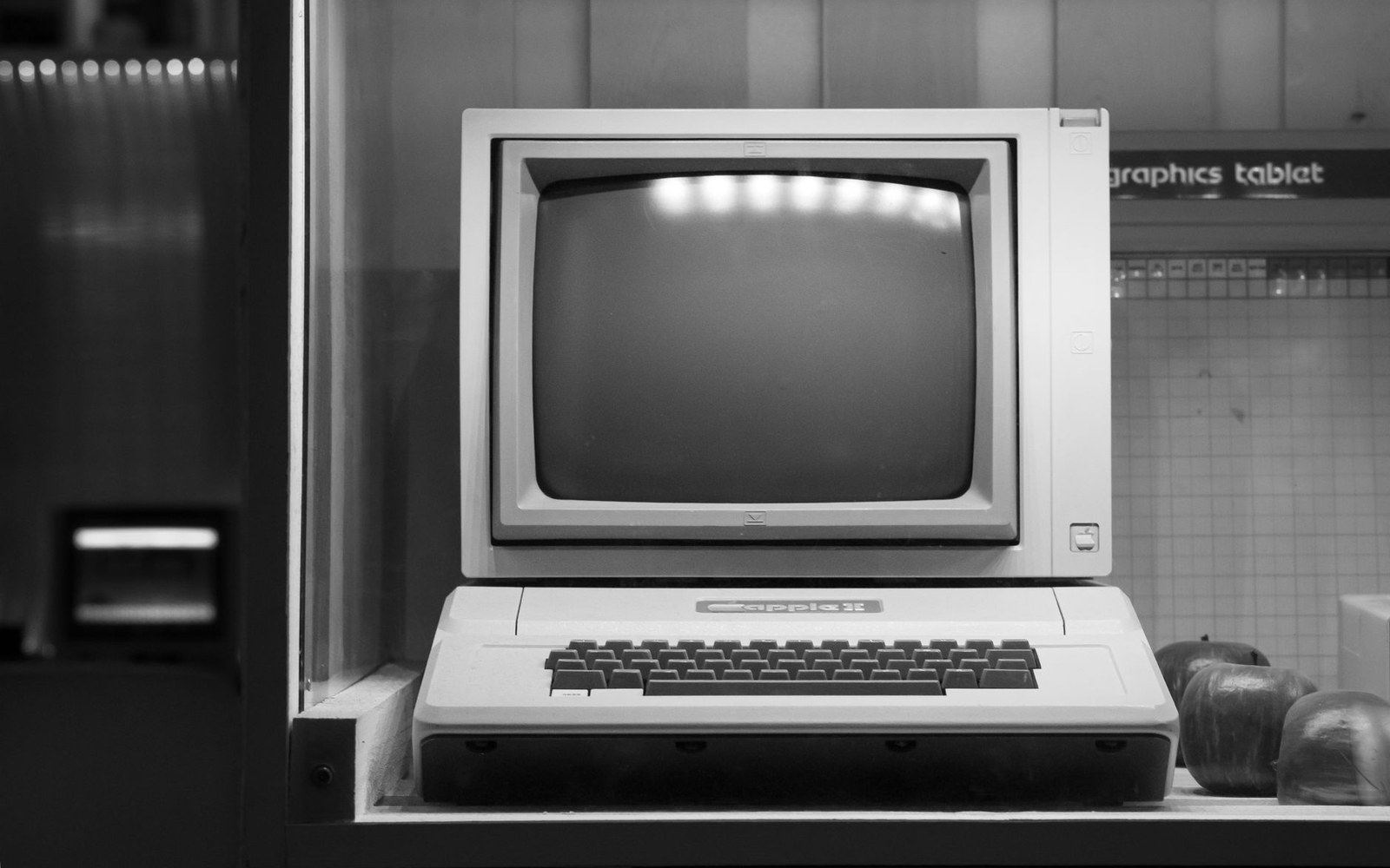 An Apple II computer with keyboard and monitor displayed on a shelf