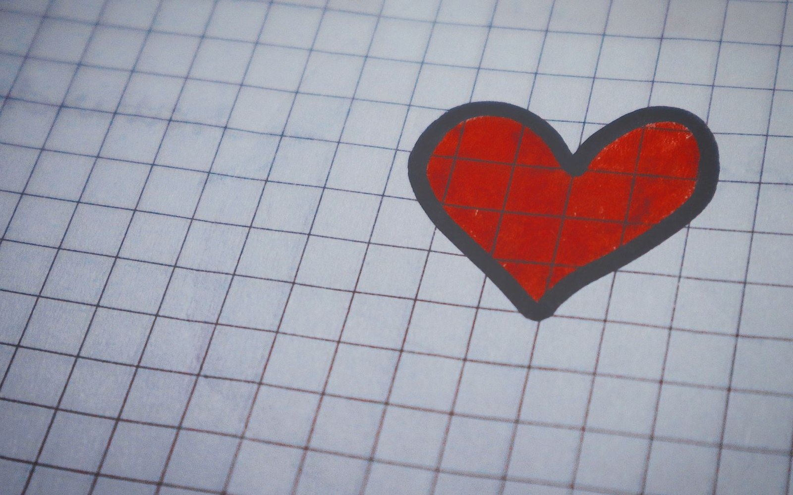 A red heart drawn on graph paper, outlined in dark gray ink