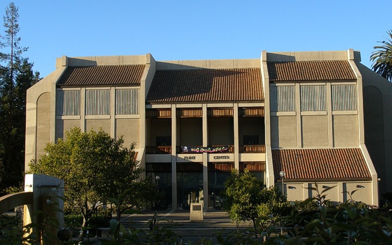 Flint Center's tiled facade and columned entrance framed by trees under blue sky